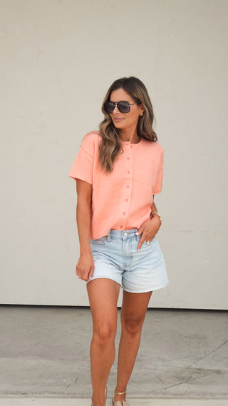 Women's coral short-sleeve button-front cardigan paired with light wash denim shorts
