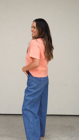 Women's coral short-sleeve button-front cardigan paired with light wash denim shorts