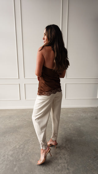 Strapless chocolate brown satin top with lace trim hem styled with ivory wide leg pants and nude heels.