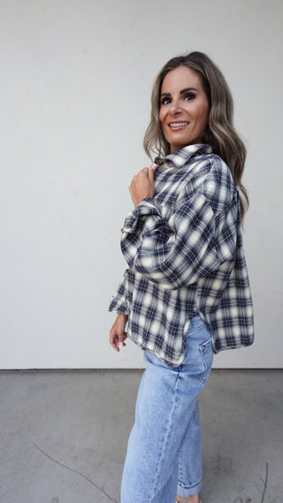 Woman wearing a plaid shirt and jeans against a plain background